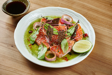 Fresh and delicious sashimi salmon and with green sause and wasabi in a white bowl on a wooden background