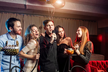 good-looking cheerful happy young people have party time in karaoke bar, wearing party dresses and shirts. Holiday, celebration, party concept