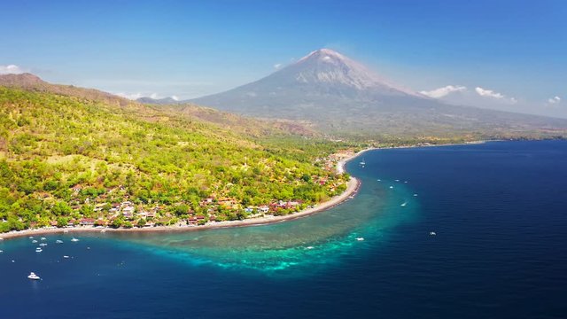 Panoramic view of the Jemeluk Bay, Amed village, the Agung volcano mountains and the azure sea in Bali, Indonesia. Aerial view 4K