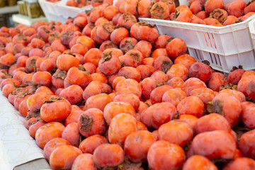 A view of a table full of fuyu persimmon fruit on display at a local farmers market.