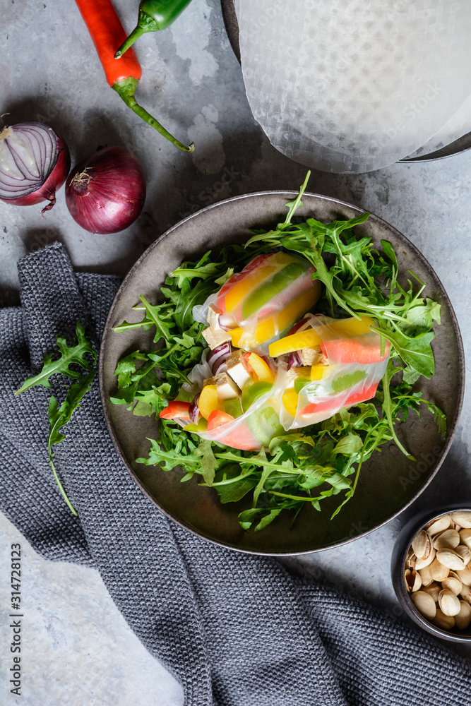 Wall mural Bell pepper, smoked tofu and red onion rice paper rolls served with fresh arugula and pistachios