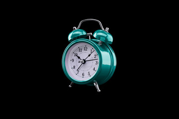 Turquoise alarm clock close-up isolated on dark background.