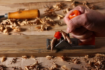the process of planing a wooden board with a hand plane in a carpenter's workshop