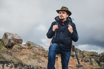 tourist in green hat, blue jacket walking on the mountain, adventure concept. close up photo