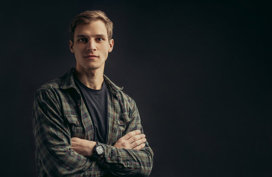 portrait of young confident caucasian man in checkered casual shirt looking at camera isolated over black background