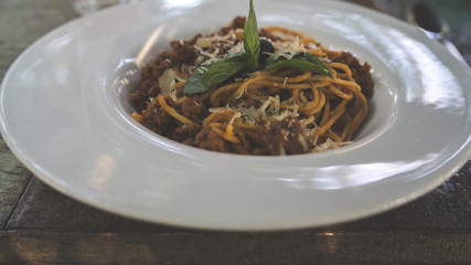 Yummy pasta on cafe table. Close-up of a plate with a portion of delicious pasta with minced meat, put on the table in a restaurant