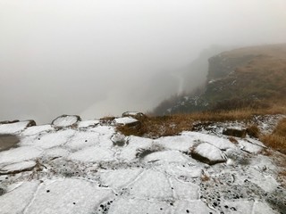 End of the world feeling at the cliffs of the Gullfoss Waterfall in Iceland: Frosted foggy winter landscape with rocks, cascades in the background and snow covered icelandic scenery in November