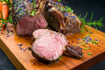 Gegrilltes Lamm Karree mit Karotten und Kräuter angeboten als closeup auf einem Modern Design Holz Board  © HLPhoto
