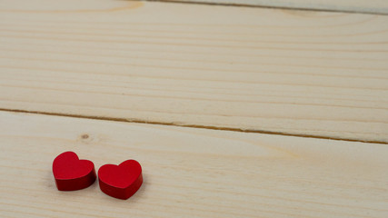 Two red hearts lying on a wooden table.