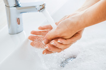 Hygiene concept. Woman washing hands under the faucet with pure clear water.