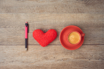 Love for coffee concept. Coffee cup, heart shape and pen on wooden background.