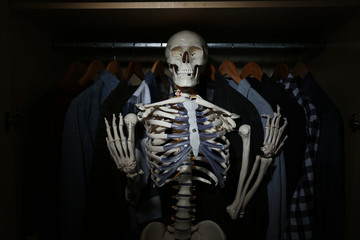 Artificial human skeleton model among clothes in wardrobe