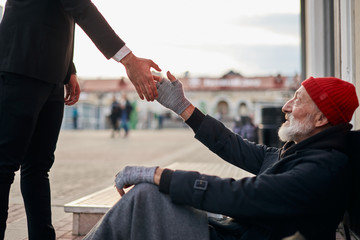 Senior beggar sitting beside street with request help with receive some coins from kind business...