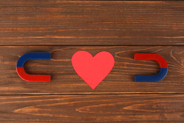 Magnets and red heart on wooden table, flat lay