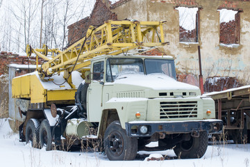  Old broken truck crane with a yellow arrow and a white cab. Winter.