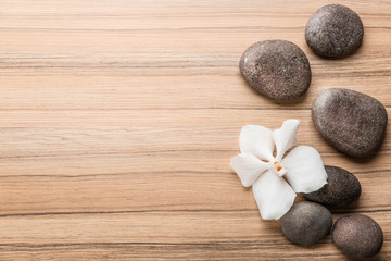 Fototapeta na wymiar Stones and orchid flower on wooden background, top view with space for text. Zen lifestyle