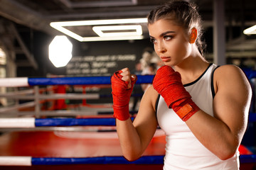 Fototapeta na wymiar Tactical efficiency of young fit caucasian woman in ring, training, boxing in sportive wear. Professional fighter, female boxer in red protective gloves