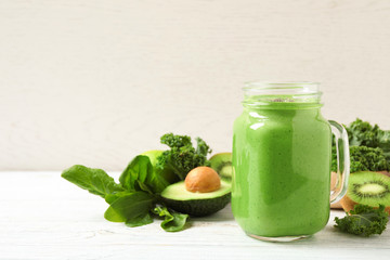 Tasty fresh kale smoothie on white wooden table