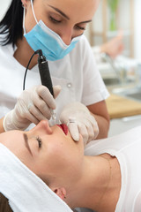 Kosmetyczka wykonuje makijaż permanentny ust. Usta po makijażu permanentnym w salonie urody. Mikropigmentacja ust zabieg w salonie medycyny estetycznej. 