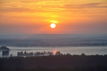 Sunrise over a picturesque landscape covered with cold fog. Early morning. Beautiful natural scenery.
