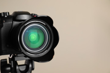 Professional video camera on beige background, closeup. Space for text