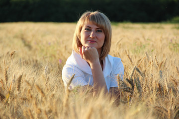 Portrait of a girl sitting in spikelets of wheat