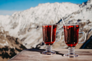 Two glasses with mulled wine on a background of mountains close-up.