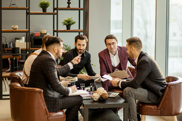 young caucasian business partners sharing and commenting reports. holding papers and notebooks, making notes and keep records of their market, in formal wear, isolated in modern office