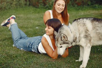 Naklejka na ściany i meble Beautiful girls in a white t-shirt. Women in a summer park. Lady with a dog