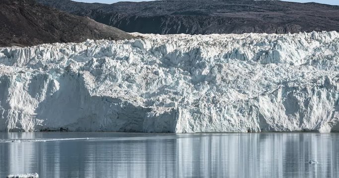 4k moving Timelapse Video clip of Eqip Sermia Glacier Eqi glacier in Greenland called the calving glacier. Huge glacier wall of ice. Large chunks of ice falling off. Close to Port Victor. Hikers