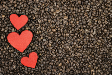 Roasted coffee beans and three red hearts. Full frame.