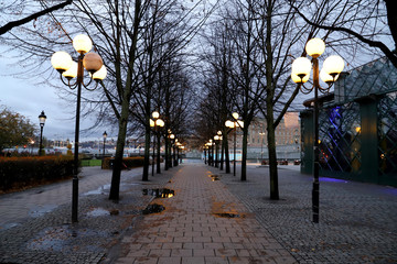 Footpath by dusk, with dark trees and lanterns in Stockholm Sweden in fall season Next to the river