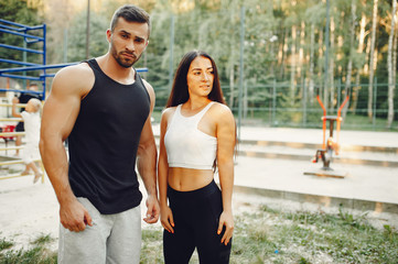 Couple training. Guy in a sports shorts. Girl in a summer park