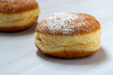 Two donuts in close-up, isolated on white marble backdrop. Filled with jam.