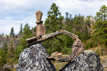 Medium shot of unusual inukshuk stone figure stands balanced on rock. Structure made with rocks,...