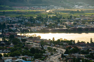 Fototapeta na wymiar Osoyoos - city on the lake shore, Okanagan Valley, British Columbia, Canada. Landscape of valley with house rooftops and agricultural lands at sunset
