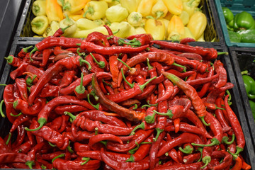 Red hot peppers in a basket on a store counter. A large number of pods of red chili.