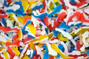 Fototapeta premium Colorful jelly sweets top view. Delicious marmalade. Candy in the form of fish blue, yellow and red, background.