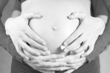 male and female hands on the belly of a pregnant woman