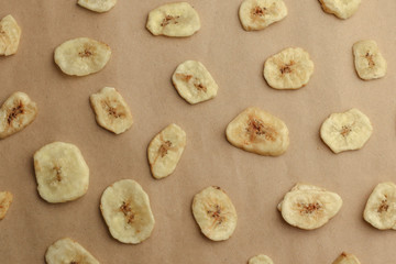 Tasty banana chips on brown background