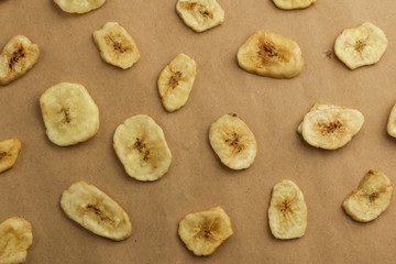 Tasty banana chips on brown background