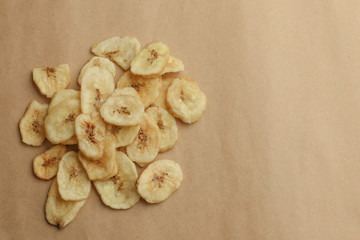 Tasty banana chips on brown background