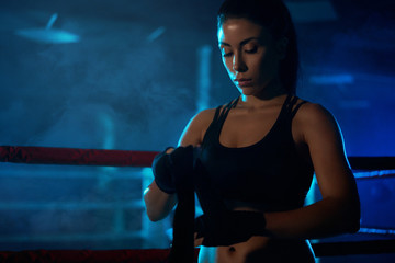 Female boxer binding the bandage on hand.