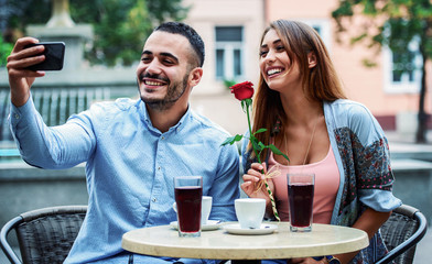Couple sitting in the cafe and making a selfie with mobile phone. Relationships, love, romance, lifestyle, technology concept