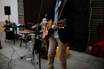 A young man playing an acoustic guitar in the street