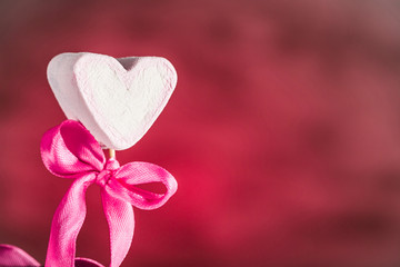 Marshmallow in the form of a heart with a bow on a stick on a pink background