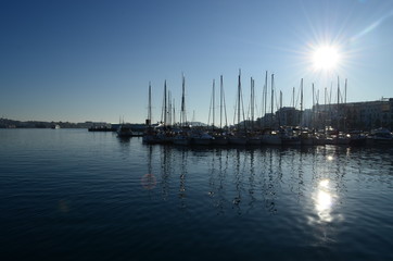 sol entre los pilares de veleros atracados