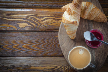 croissant and cup of coffee on wooden table