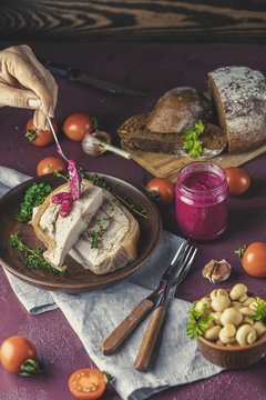 Woman dressing tasty baking pork lard bacon fatback with black pepper and other herbs and spices in ceramic dish. Traditional Ukrainian, Hungarian, Polish or other Eastern Europe national dish