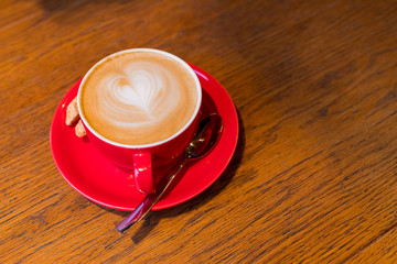 coffee-break. Red cup of cappuccino with beautiful latte art on old wooden background. Latte art coffee.aroma coffee in red ceramic cup. Copy space.wood table in cafe, restaurant